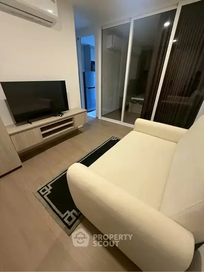 Modern living room with sleek furniture and sliding glass doors leading to a bedroom.