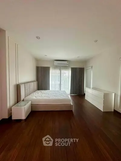 Spacious bedroom with modern furnishings and large window for natural light.