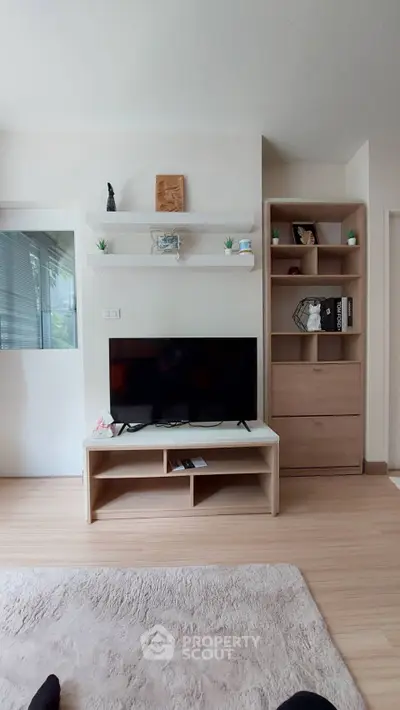 Modern living room with sleek TV stand, shelves, and cozy decor in a stylish apartment.
