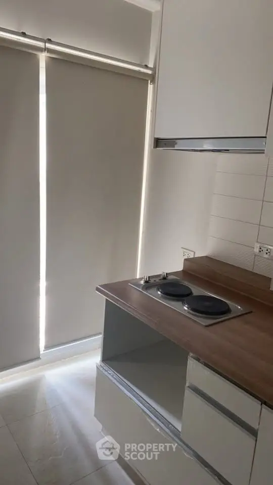 Compact kitchen with electric stove and modern cabinetry in a cozy apartment.