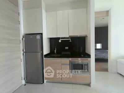 Modern kitchen with sleek appliances and adjacent view into a cozy bedroom.