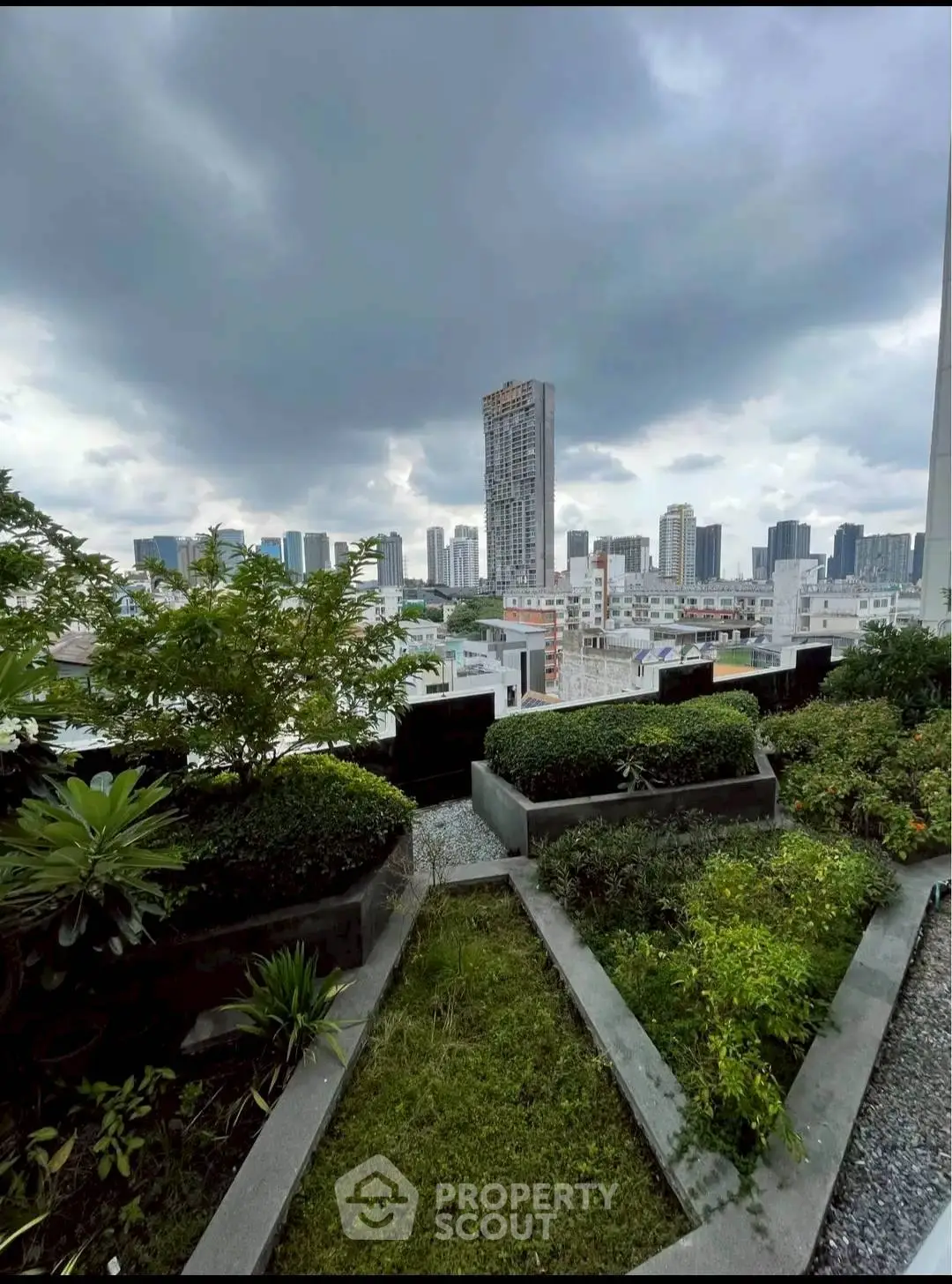 Stunning cityscape view from a lush rooftop garden with dramatic sky.