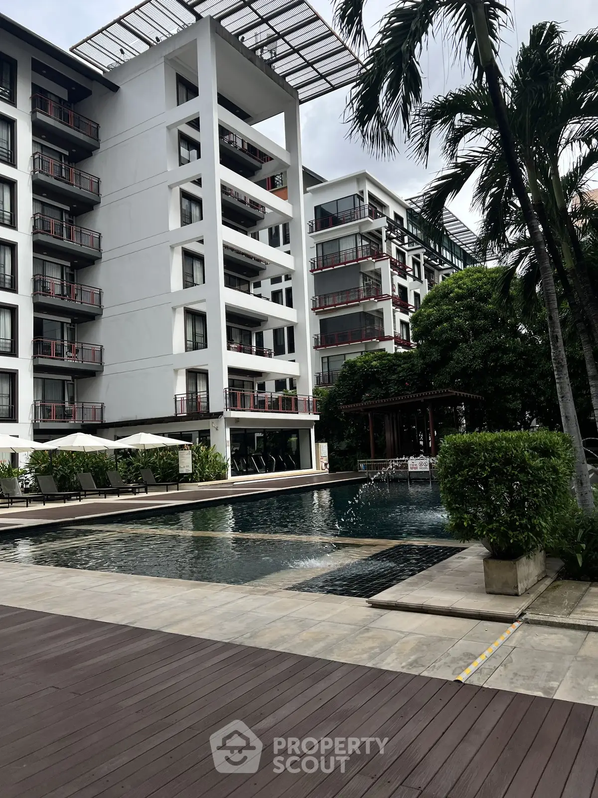 Luxurious apartment complex with modern pool and lush greenery, perfect for upscale living.