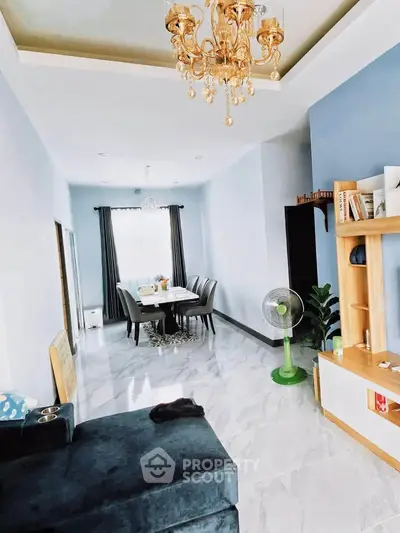 Elegant living room with chandelier and dining area, featuring modern decor and spacious layout.