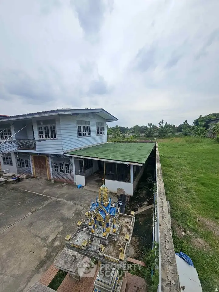 Spacious property with green lawn and unique outdoor shrine, ideal for serene living.