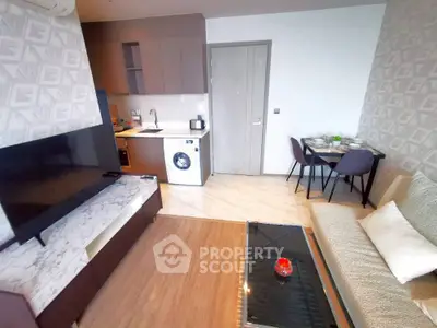 Modern living room with open kitchen and stylish decor, featuring a washing machine and cozy dining area.