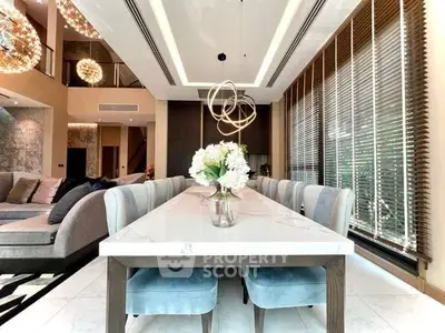 Luxurious dining area with modern chandelier and elegant decor in a spacious open-plan living room.