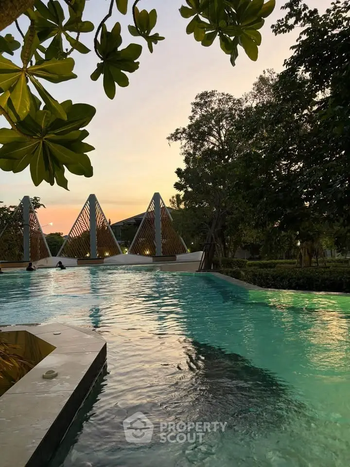 Luxurious outdoor pool area with modern architectural design and lush greenery at sunset.