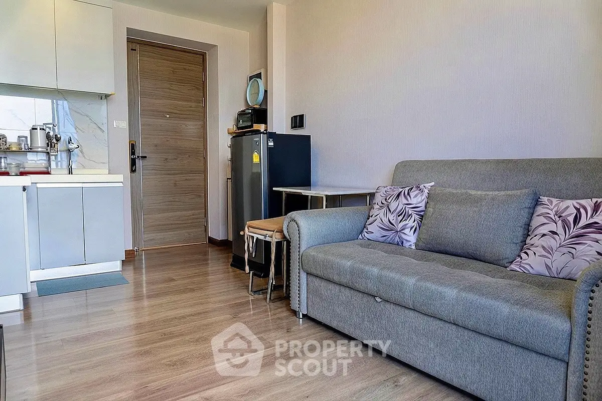Modern living room with cozy sofa and compact kitchen in open layout apartment.