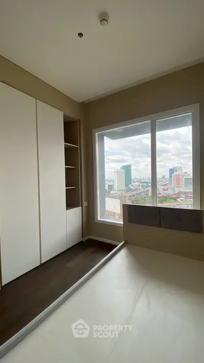 Modern bedroom with built-in storage and stunning city view from large window.