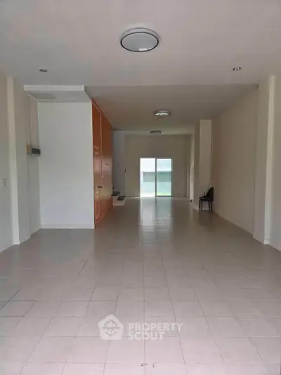 Spacious open-plan living area with tiled flooring and sliding glass doors leading to a balcony.