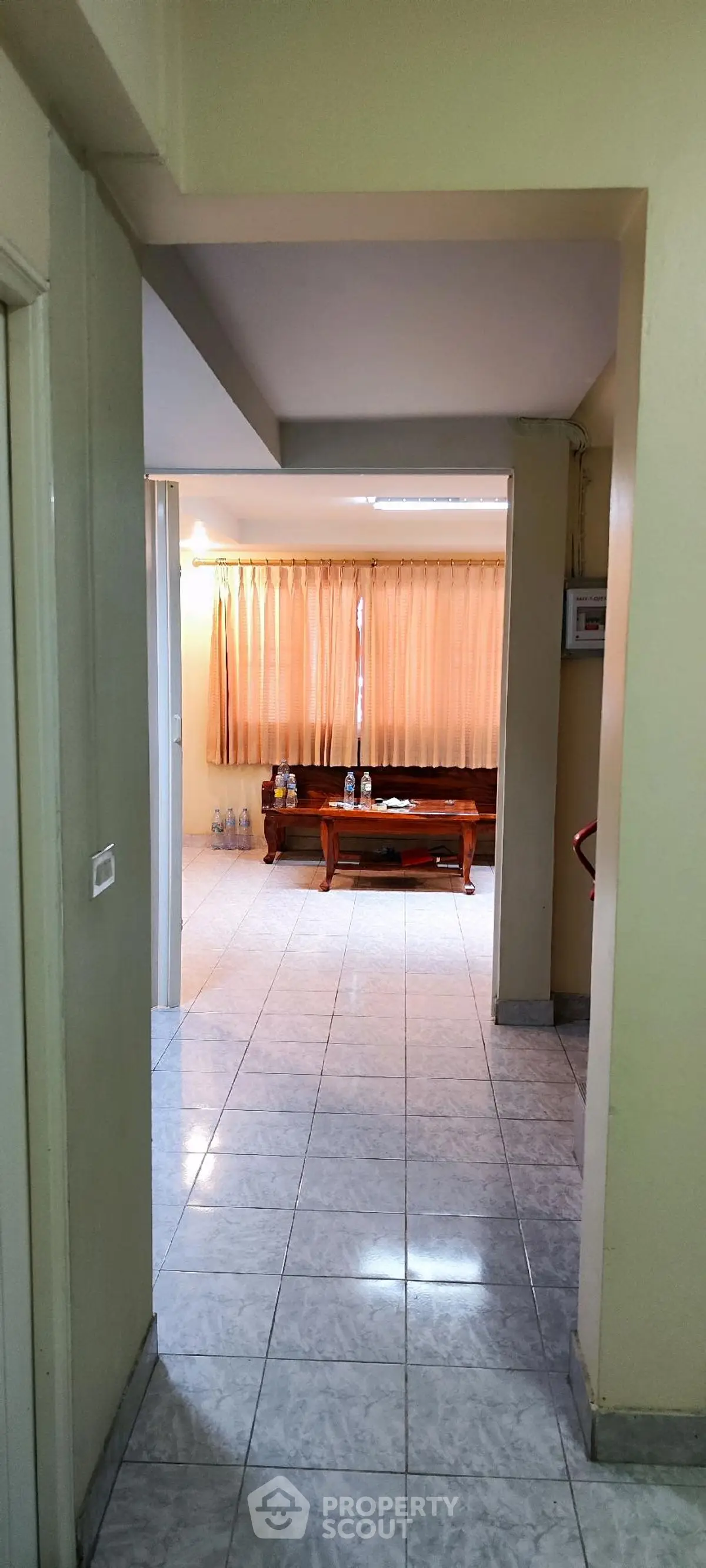 Spacious living room with tiled flooring and large windows for natural light.
