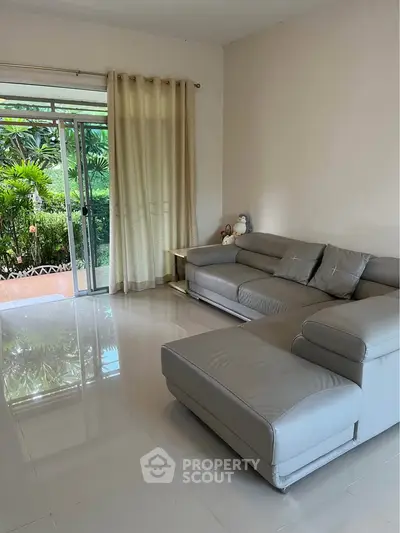 Spacious living room with modern sofa and garden view, perfect for relaxation and entertaining.