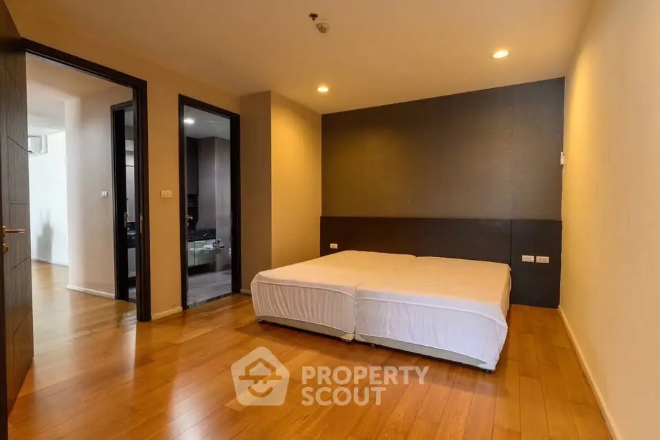 Spacious bedroom with wooden flooring and modern design in a stylish apartment.