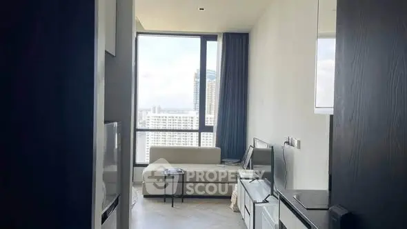 Modern living room with large window and city view, featuring sleek furniture and minimalist design.