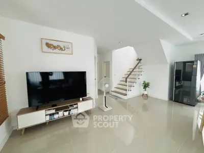Modern living room with sleek TV setup and elegant staircase