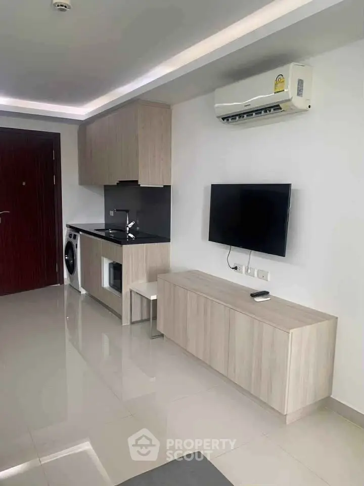 Modern living room with sleek kitchen, TV, and air conditioning in a stylish apartment.