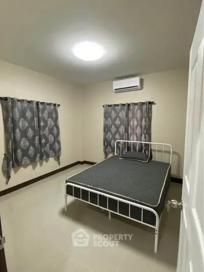 Cozy bedroom with modern decor and ample natural light, featuring a comfortable bed and stylish curtains.