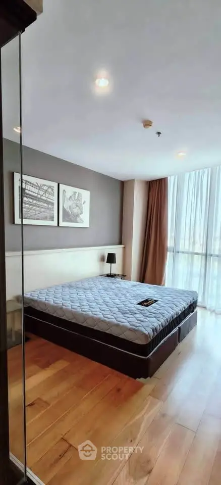 Spacious bedroom with large window and modern decor in a high-rise apartment.