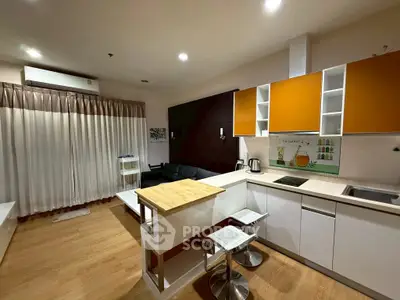 Modern open-layout kitchen with stylish orange cabinets and cozy living area.