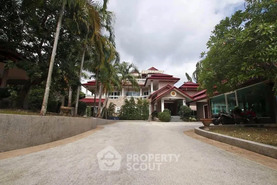 Stunning multi-story house with red roof and lush greenery, offering a luxurious and serene living environment.