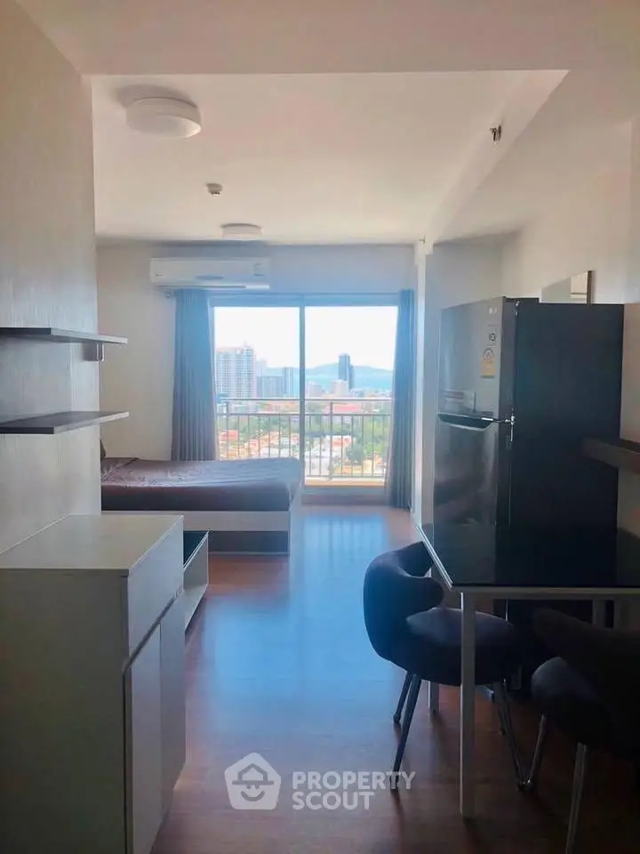 Modern studio apartment with open layout and stunning city view from large window.