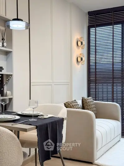 Modern living room with elegant dining area and cozy sofa, featuring stylish lighting and large window blinds.