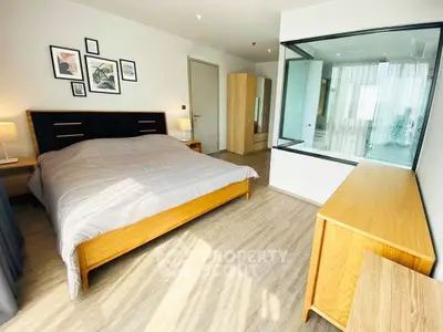 Spacious modern bedroom with wooden furniture and large window view