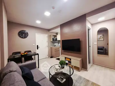 Modern living room with sleek furniture and wall-mounted TV in cozy apartment.