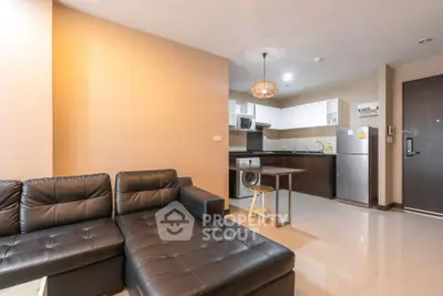 Modern open-plan living room with sleek kitchen and stylish black leather sofa.