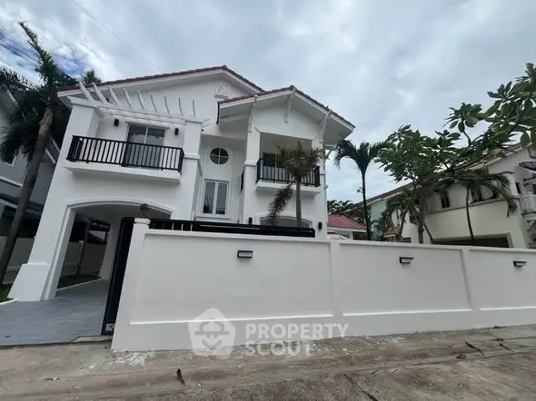 Stunning white two-story house with modern balcony and lush palm trees