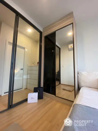 Modern bedroom with mirrored wardrobe and wooden flooring