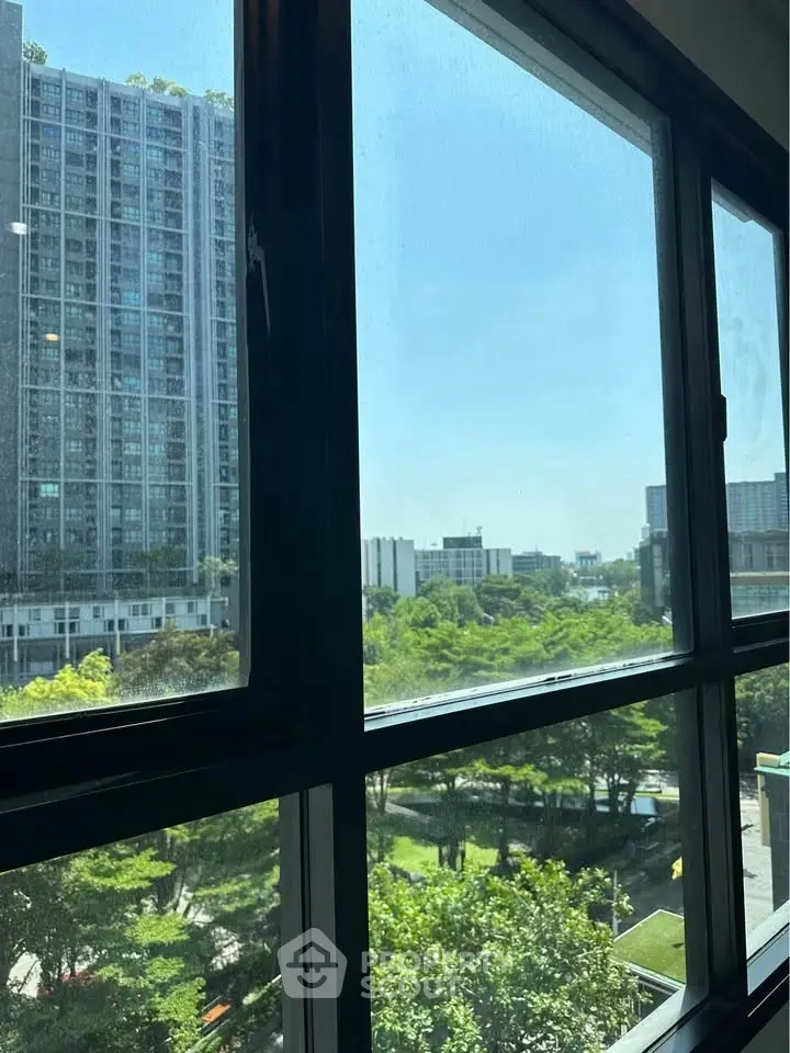 Stunning cityscape view from a modern apartment window, showcasing lush greenery and urban skyline.