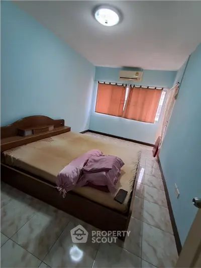 Cozy bedroom with air conditioning and natural light, featuring a comfortable bed and tiled flooring.