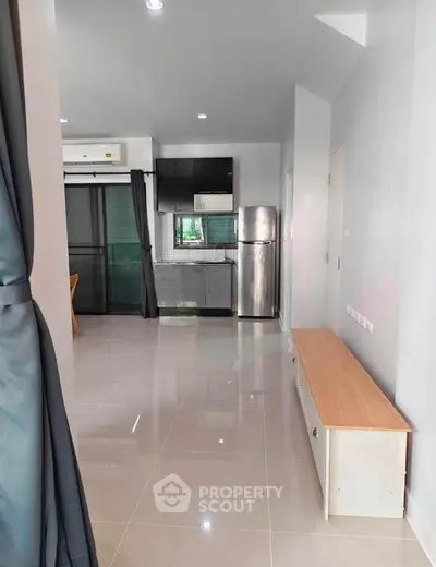 Modern apartment interior with sleek kitchen and spacious living area, featuring stainless steel appliances and bright lighting.