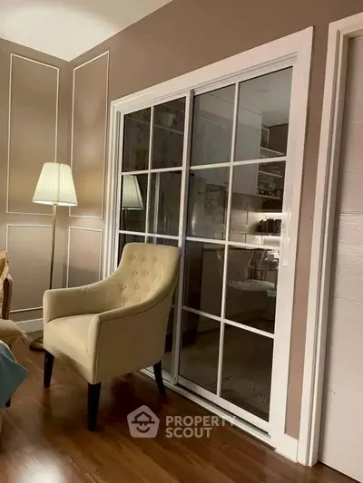 Elegant living room with plush armchair and stylish decor, featuring warm lighting and wooden flooring.
