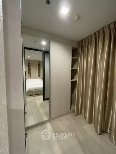 Modern bedroom with elegant curtains and mirrored wardrobe, showcasing a cozy and stylish interior design.
