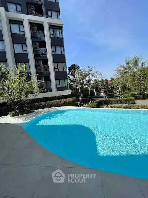 Luxurious apartment building with a sparkling pool and lush greenery, perfect for relaxation and leisure.