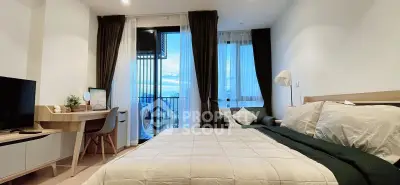 Modern bedroom with balcony view, stylish decor, and natural light.