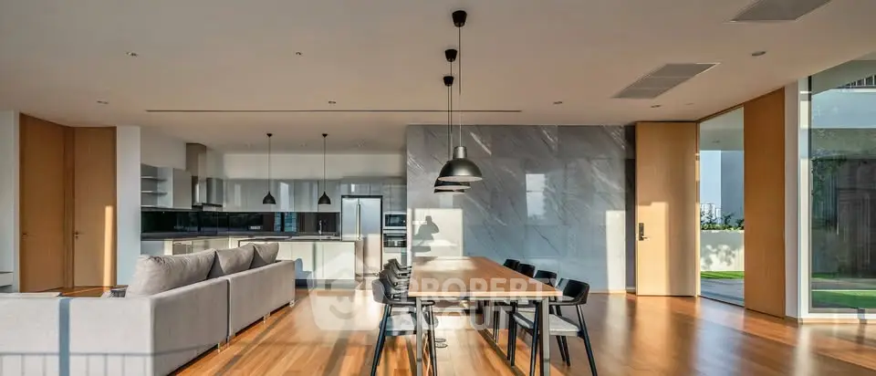 Spacious modern living room with open kitchen and elegant dining area, featuring sleek design and abundant natural light.