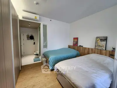 Modern bedroom with two beds, wooden flooring, and minimalist decor in a cozy apartment.