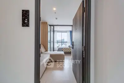 Modern apartment entrance leading to a cozy living room with a view of the bedroom.