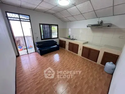 Cozy kitchen with open layout and tiled flooring, featuring a comfortable sofa and ample natural light.