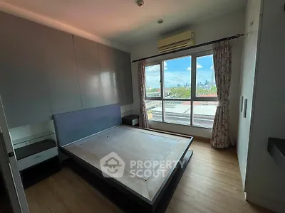 Spacious bedroom with large window offering stunning city views, featuring built-in storage and modern design.
