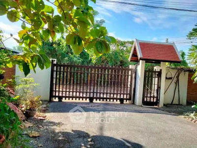 Charming gated entrance with lush greenery and traditional roof design.