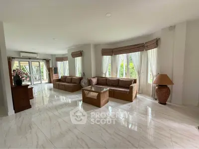 Spacious living room with elegant decor and large windows offering garden views.