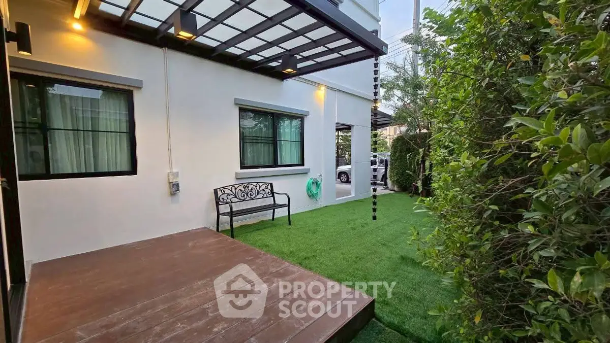 Charming garden area with wooden deck and lush greenery, perfect for relaxation.