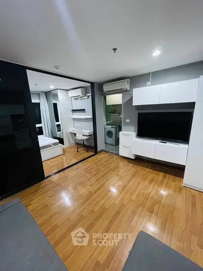 Modern apartment interior with open layout, featuring a living area, bedroom, and kitchen with washing machine.