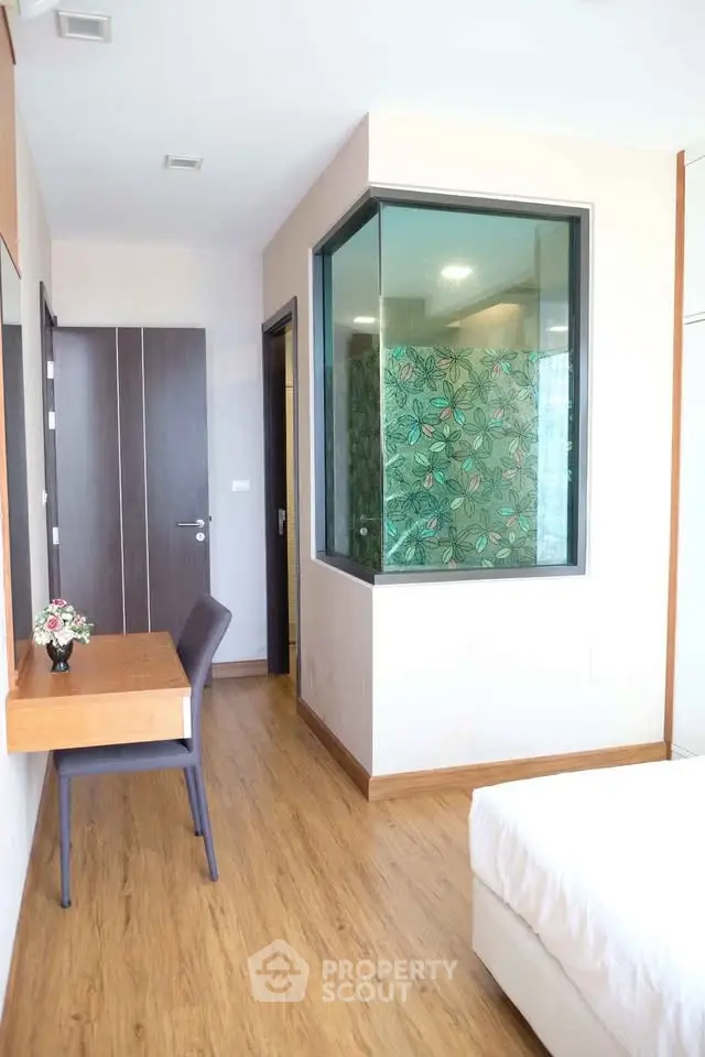Modern bedroom with wooden flooring and stylish glass partition