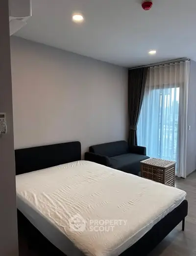 Modern bedroom with cozy bed and stylish sofa near large window with curtains.